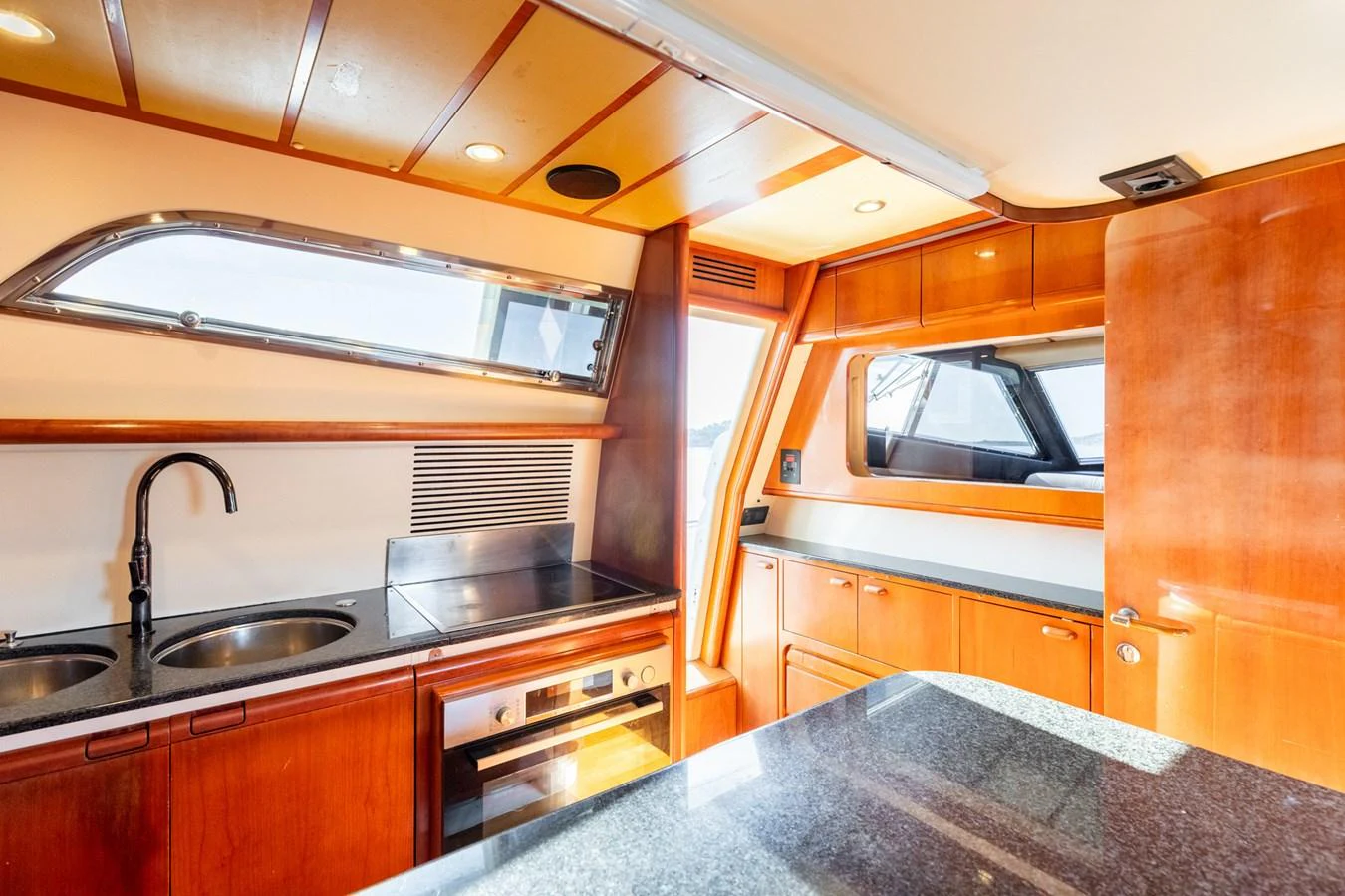 The yacht's galley is equipped with modern appliances and ample counter space, featuring warm wood finishes and natural light. aboard PUMABAY Yacht for Sale