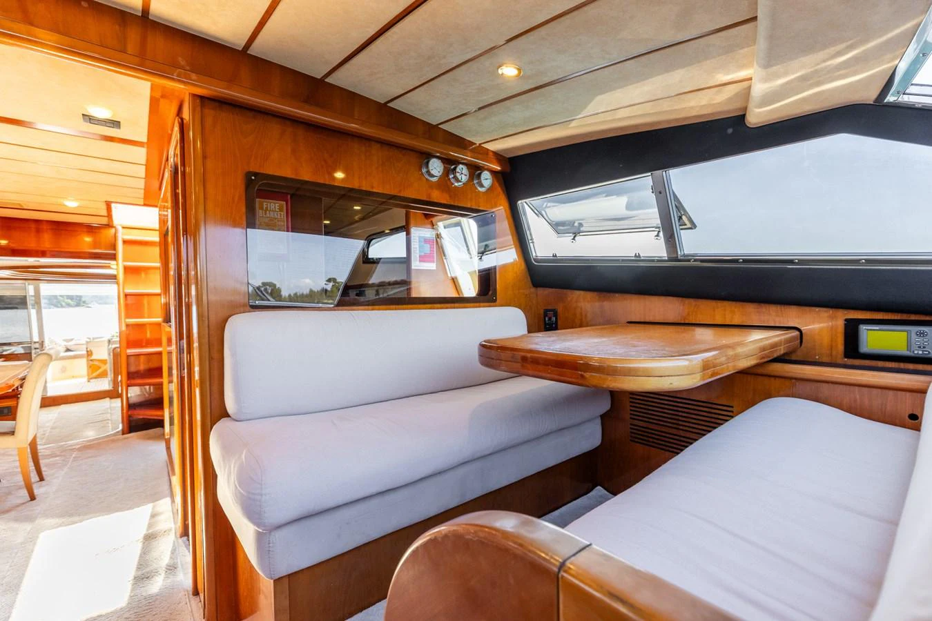 The yacht's saloon features a cozy seating area with a wooden table and large windows for natural light. aboard PUMABAY Yacht for Sale