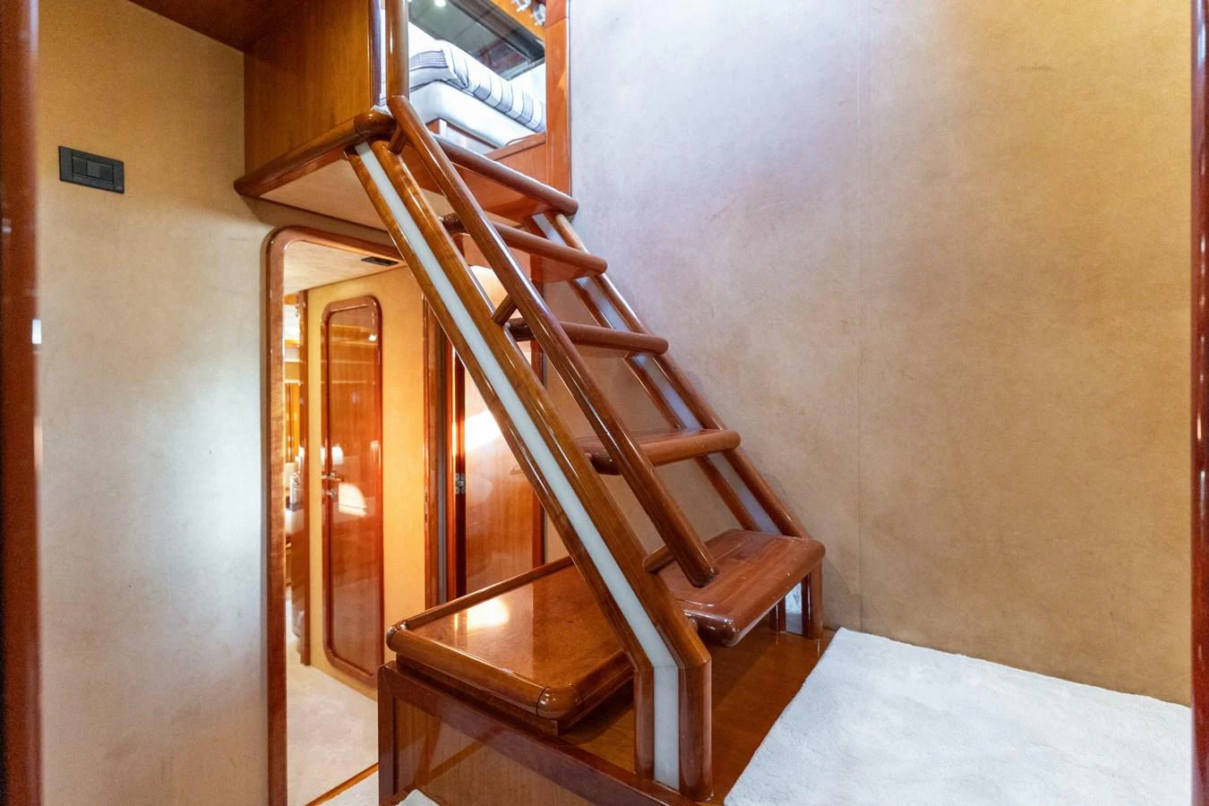 A polished wooden staircase leads to an upper level inside the yacht. aboard PUMABAY Yacht for Sale