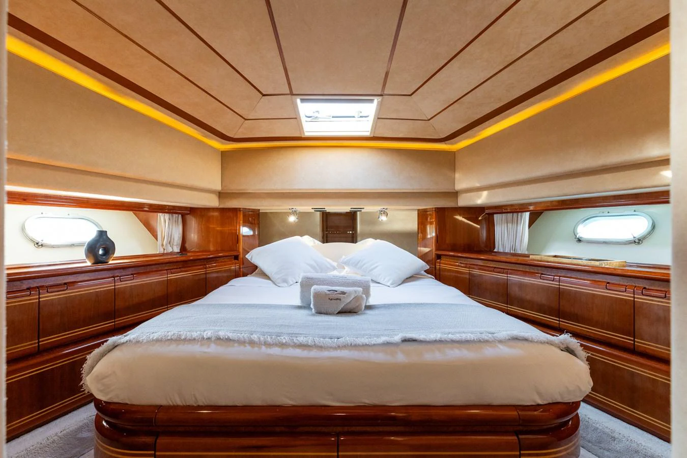The stateroom features a luxurious bed with elegant wood paneling and soft lighting. aboard PUMABAY Yacht for Sale