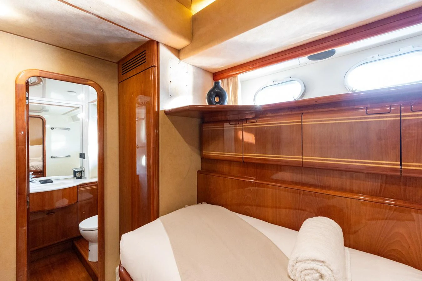 The guest stateroom features a cozy bed with a view into the ensuite bathroom, showcasing luxurious wood finishes and ample natural light. aboard PUMABAY Yacht for Sale