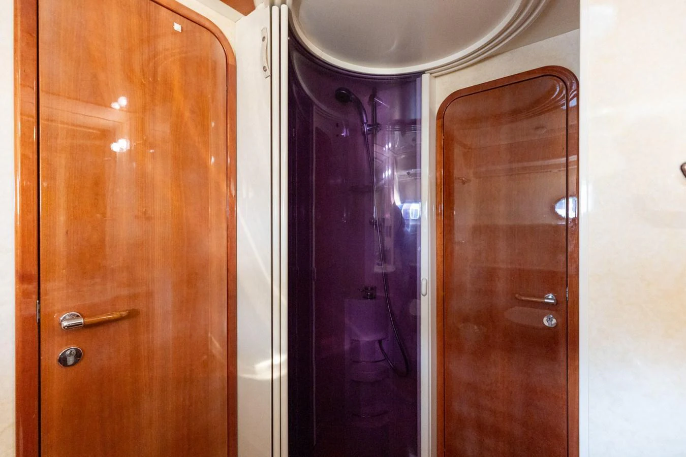 The image showcases a compact and well-appointed yacht bathroom with wooden doors and a shower cabin. aboard PUMABAY Yacht for Sale