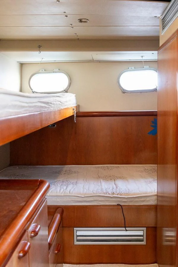 A cozy bunk cabin with wooden finishes and natural light from portholes. aboard PUMABAY Yacht for Sale