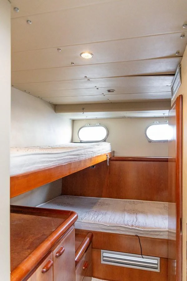 The cozy bunk cabin features wooden accents and natural light from portholes. aboard PUMABAY Yacht for Sale