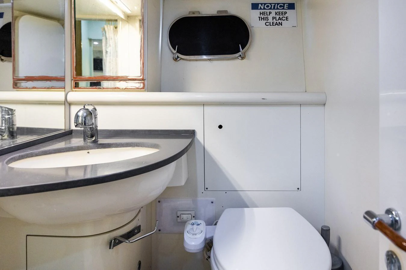 A well-maintained yacht bathroom with a sink and toilet, featuring a small window and a cleanliness notice. aboard PUMABAY Yacht for Sale