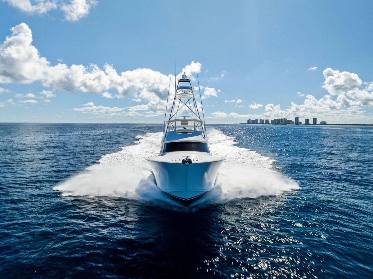 A sleek yacht cuts through the water under a bright blue sky, showcasing its powerful design. aboard CATCH 23 Yacht for Sale