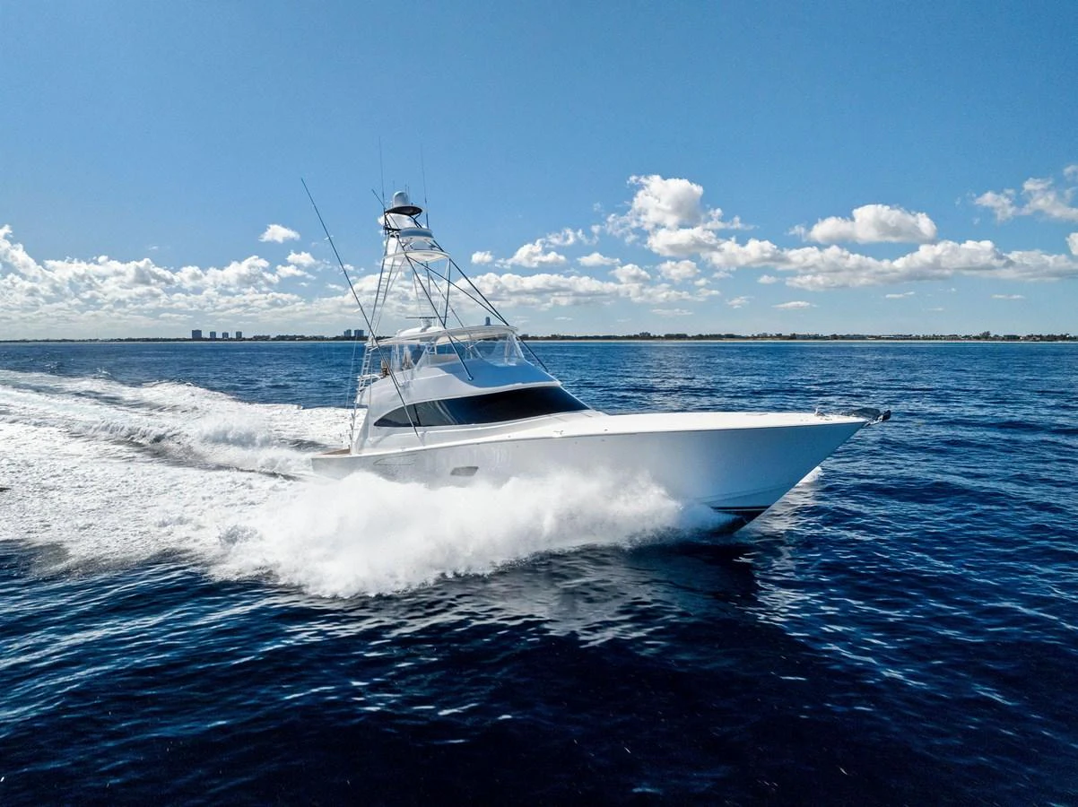 A sleek yacht cruises swiftly across the open water under a clear blue sky. aboard CATCH 23 Yacht for Sale