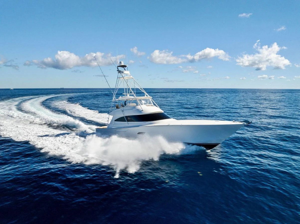 A sleek yacht cruises swiftly through the open ocean under a clear blue sky. aboard CATCH 23 Yacht for Sale