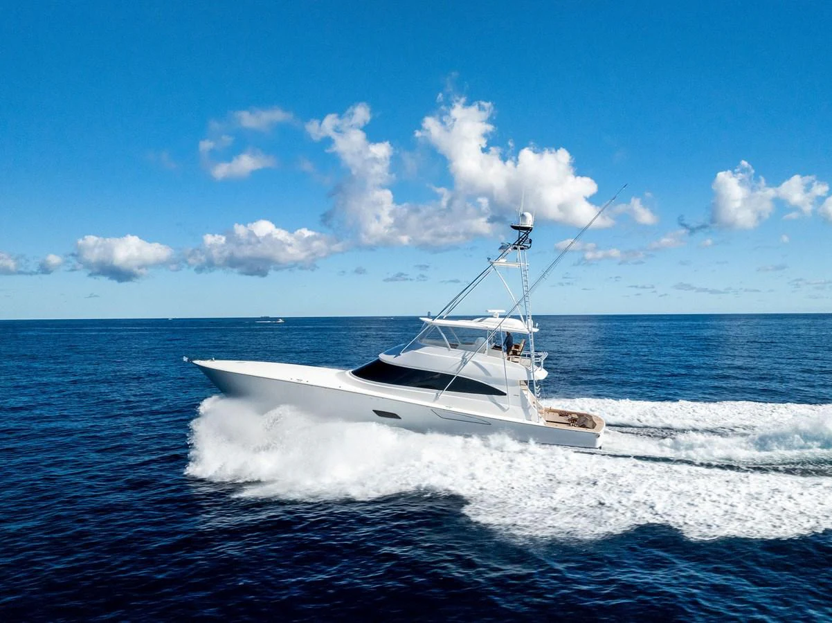 A sleek yacht cruises swiftly across the open ocean under a clear blue sky. aboard CATCH 23 Yacht for Sale