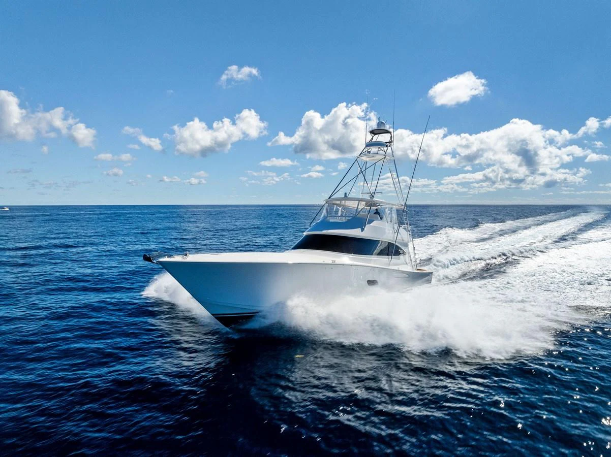 A sleek yacht cruises swiftly through the open ocean under a bright blue sky. aboard CATCH 23 Yacht for Sale