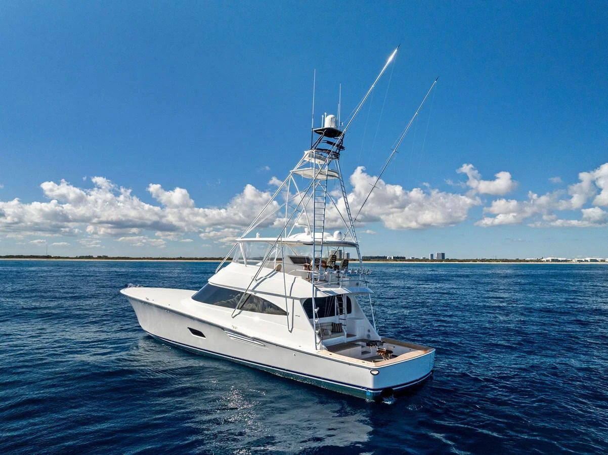 A sleek yacht cruises on a calm, blue ocean under a clear sky. aboard CATCH 23 Yacht for Sale
