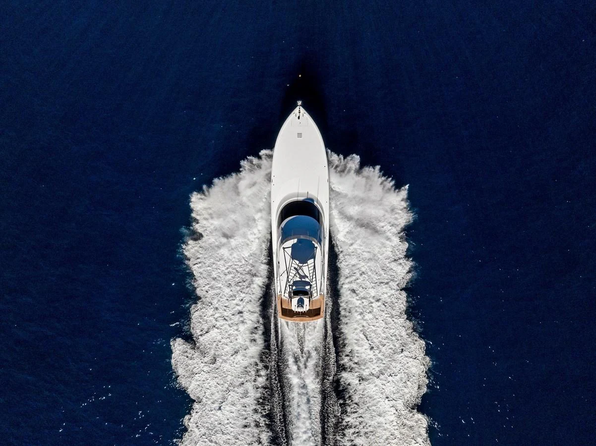 A sleek yacht cruises through deep blue waters, leaving a trail of white wake behind. aboard CATCH 23 Yacht for Sale