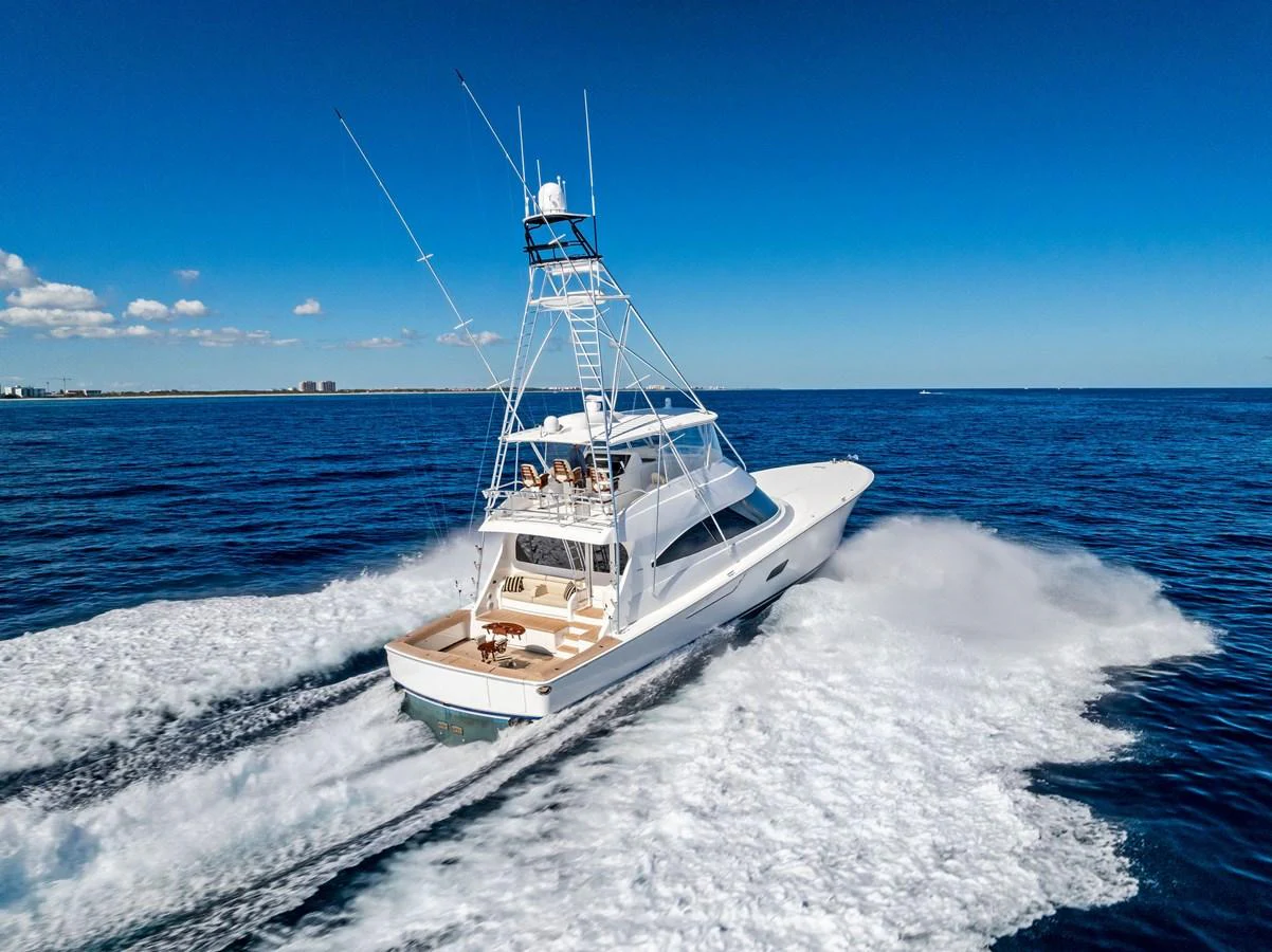 A sleek yacht cruises swiftly through the open sea under a clear blue sky. aboard CATCH 23 Yacht for Sale
