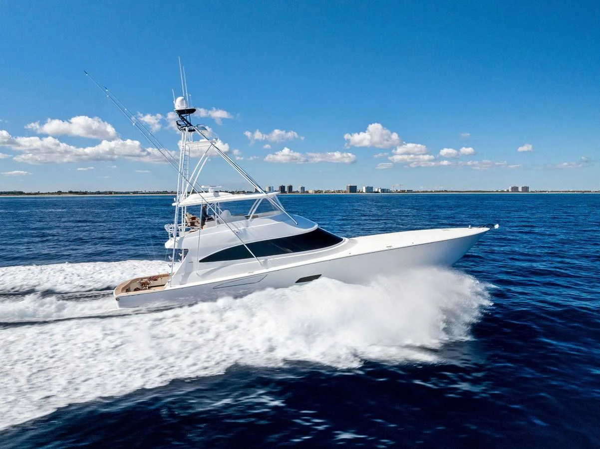A sleek yacht cruises swiftly on open water under a clear blue sky. aboard CATCH 23 Yacht for Sale