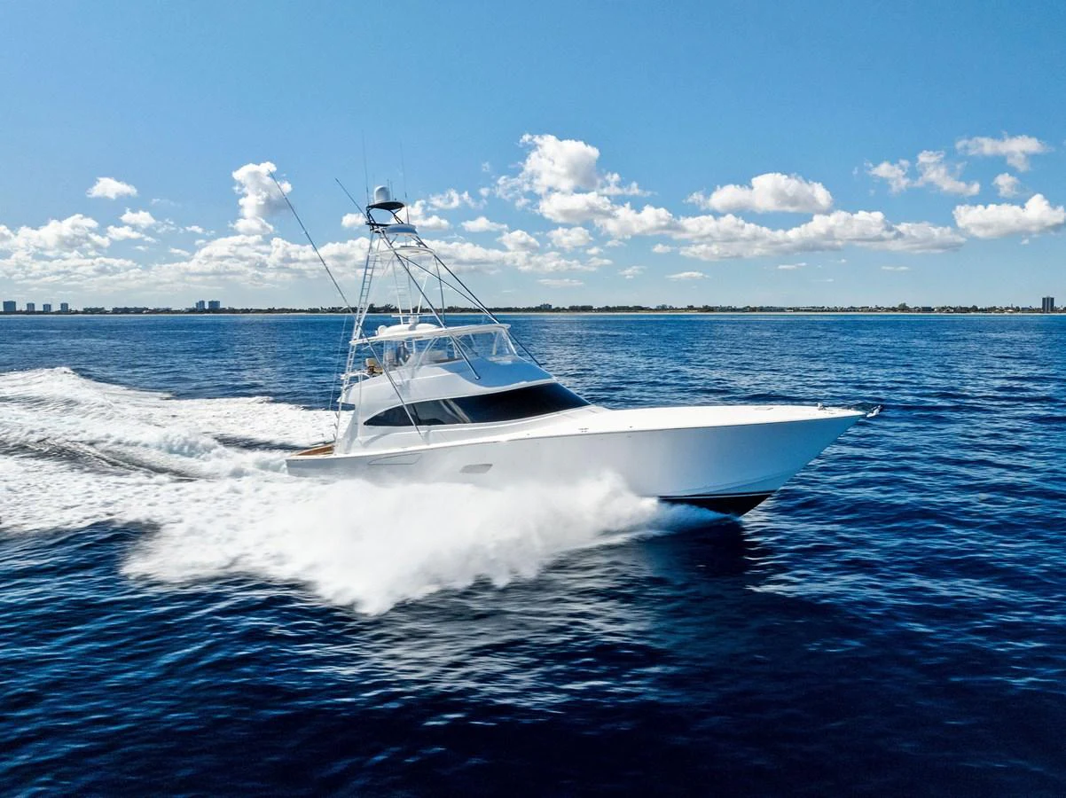 A sleek yacht cruises swiftly through the open water under a clear blue sky. aboard CATCH 23 Yacht for Sale