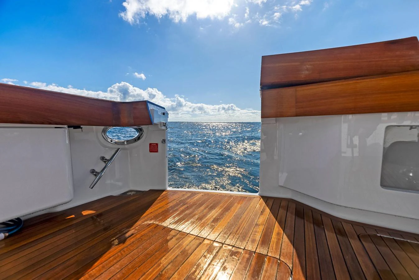 The aft deck offers a stunning view of the open sea, framed by polished wood and sleek design. aboard CATCH 23 Yacht for Sale