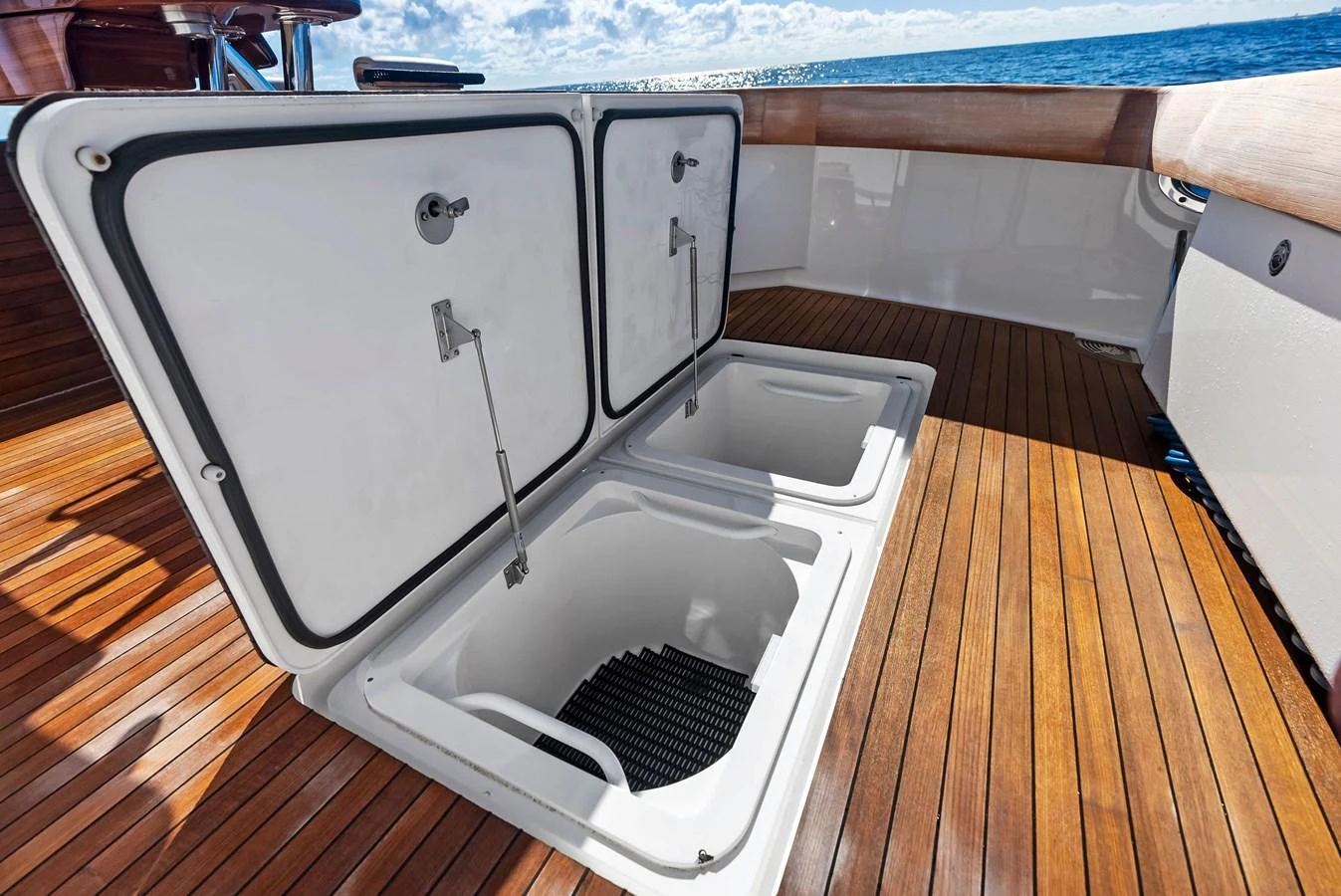 The image showcases a yacht's deck with open hatches revealing storage compartments. aboard CATCH 23 Yacht for Sale