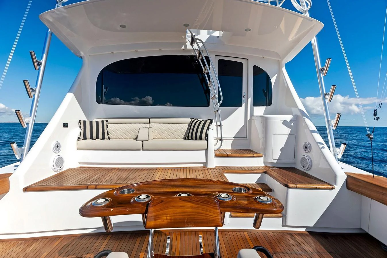 The aft deck features elegant wooden seating and a spacious lounging area with a stunning ocean backdrop. aboard CATCH 23 Yacht for Sale