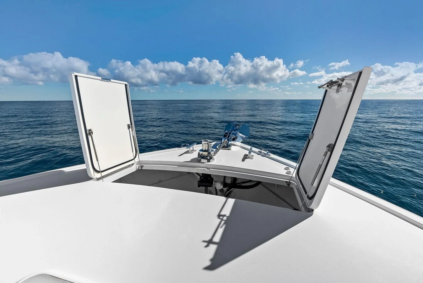 The yacht's foredeck features open hatches against a backdrop of calm sea and blue sky. aboard CATCH 23 Yacht for Sale