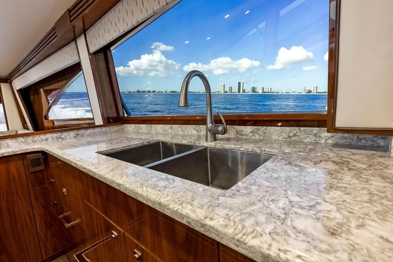 The galley features a sleek countertop with a double sink and a stunning view of the sea and skyline. aboard CATCH 23 Yacht for Sale