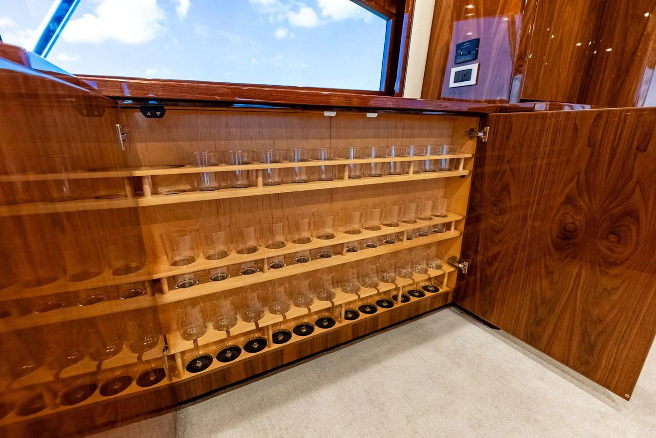 A beautifully crafted wooden cabinet with an array of glassware neatly arranged inside. aboard CATCH 23 Yacht for Sale