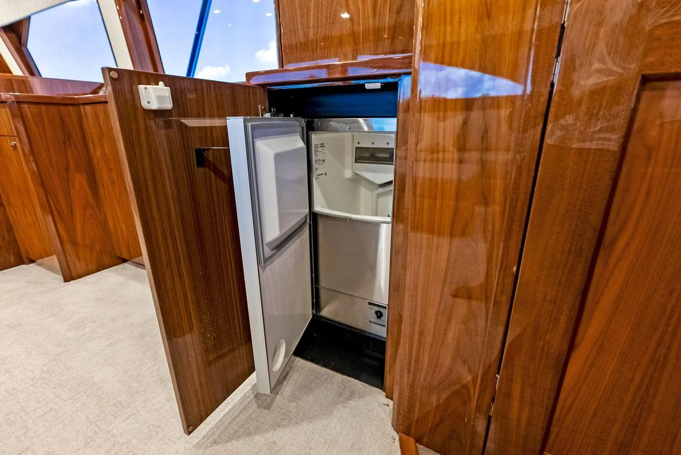 The image showcases a built-in refrigerator within the yacht's galley, featuring elegant wooden cabinetry. aboard CATCH 23 Yacht for Sale