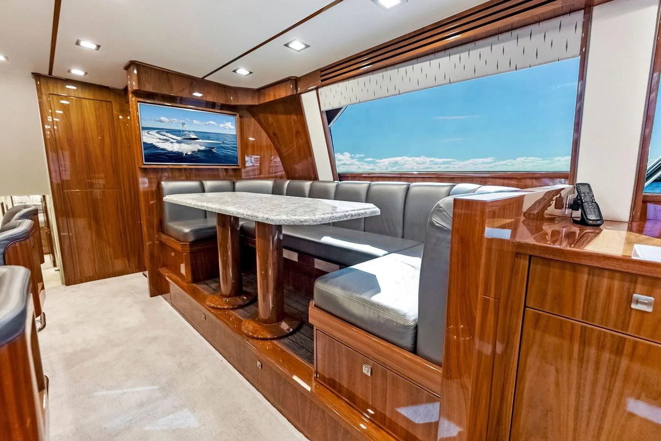 The yacht's dining area features a luxurious wooden table with plush seating and a large window offering stunning ocean views. aboard CATCH 23 Yacht for Sale