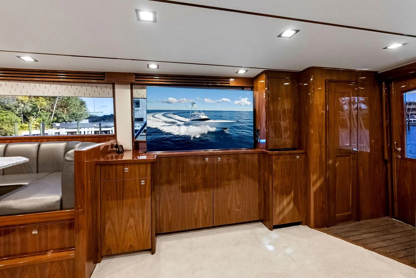 The yacht's interior features polished wood paneling and a large flat-screen TV displaying a serene ocean scene. aboard CATCH 23 Yacht for Sale