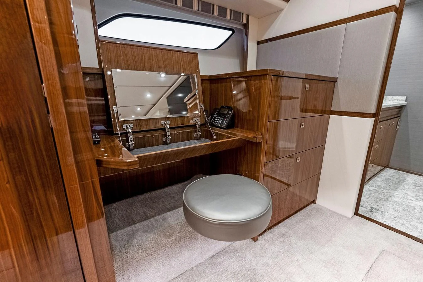 The yacht's interior features a sleek vanity area with polished wood finishes and a comfortable stool. aboard CATCH 23 Yacht for Sale