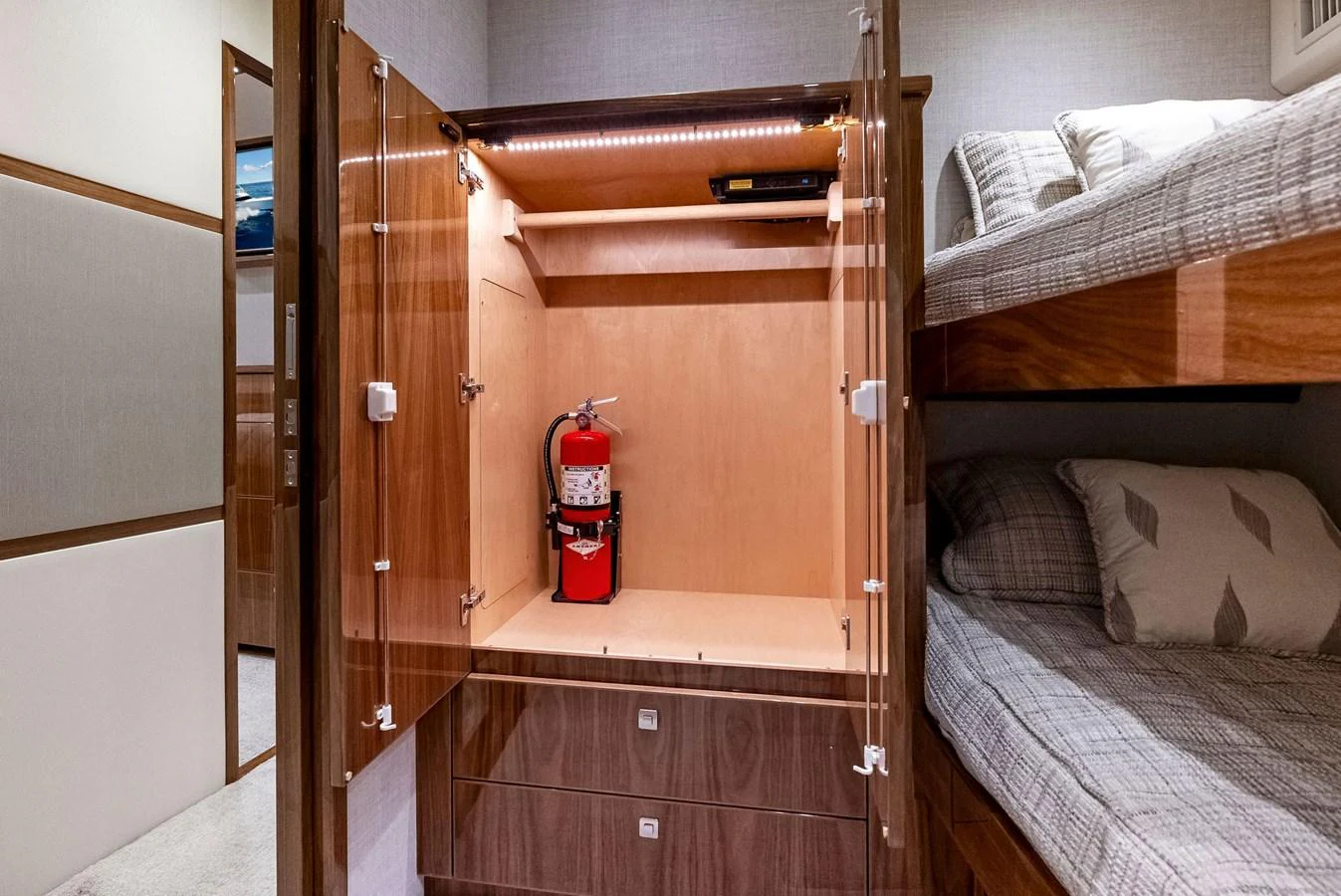 The image shows a cozy cabin with bunk beds and a storage cabinet equipped with a fire extinguisher. aboard CATCH 23 Yacht for Sale