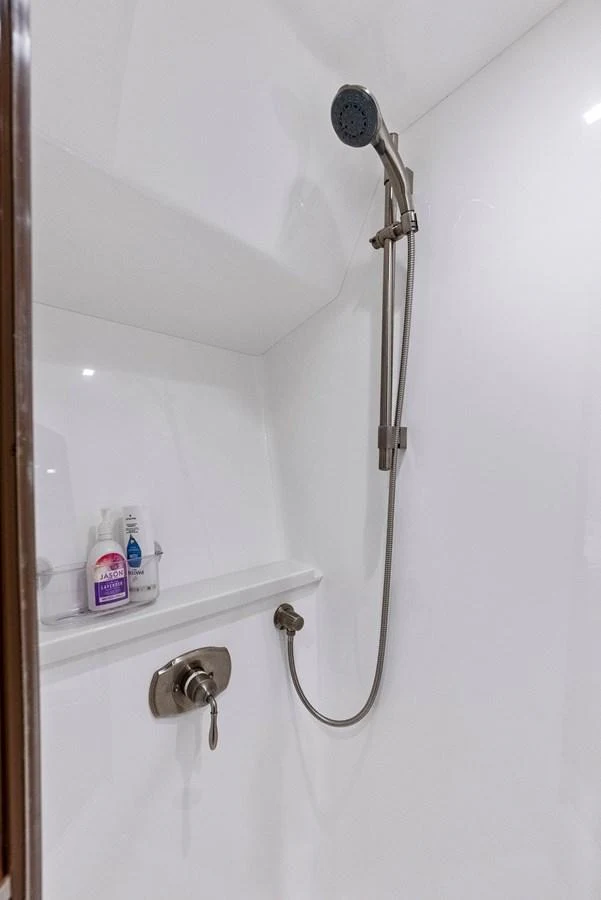 A sleek and modern shower area with stainless steel fixtures and a white backdrop. aboard CATCH 23 Yacht for Sale