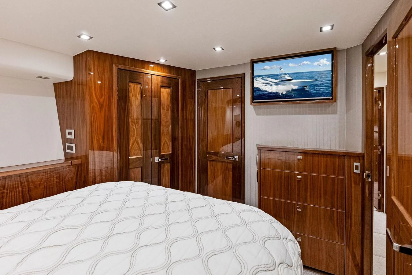 The stateroom features elegant wood paneling and a comfortable bed, complemented by a mounted TV. aboard CATCH 23 Yacht for Sale