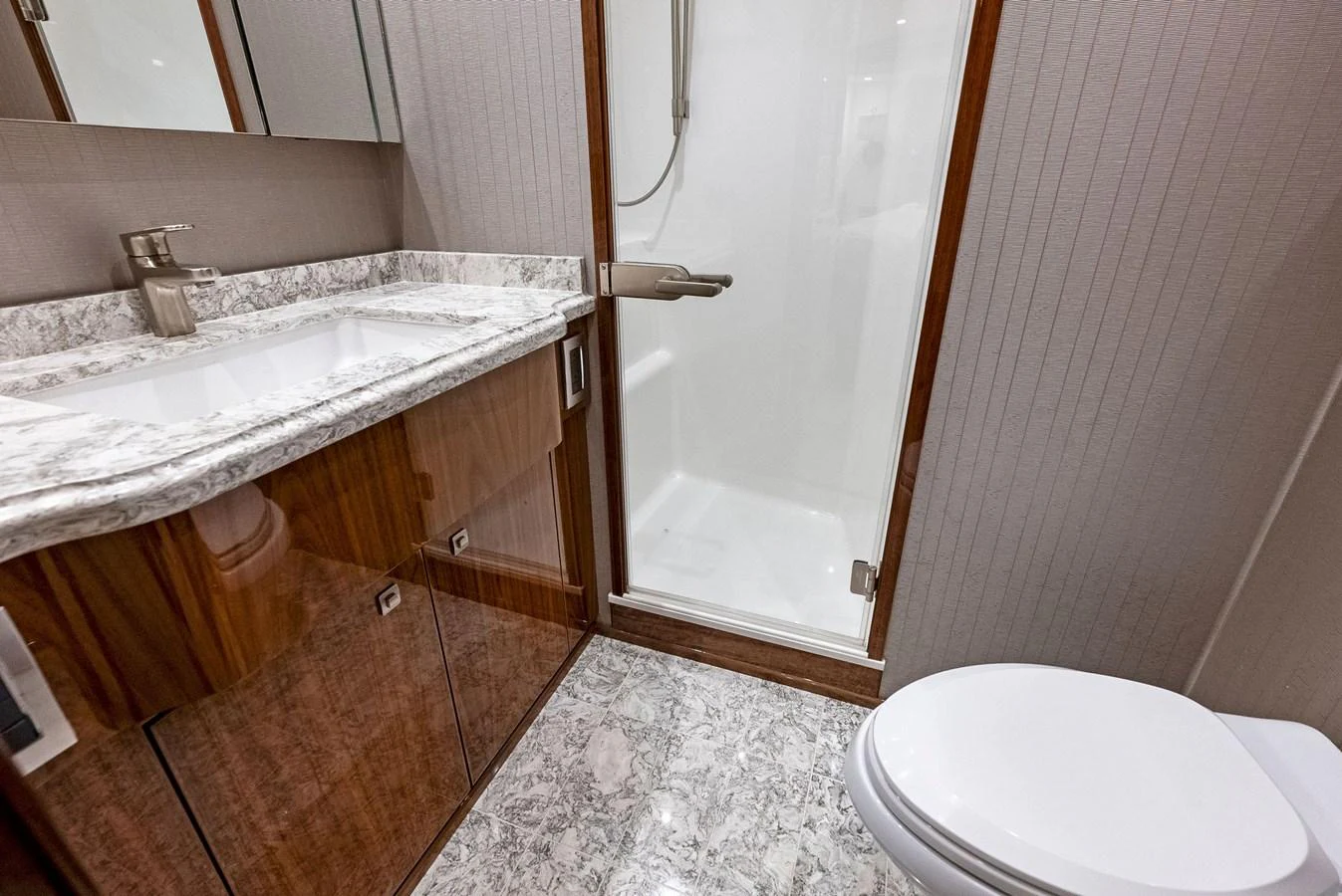 A sleek and modern yacht bathroom with a marble countertop and a glass-enclosed shower. aboard CATCH 23 Yacht for Sale
