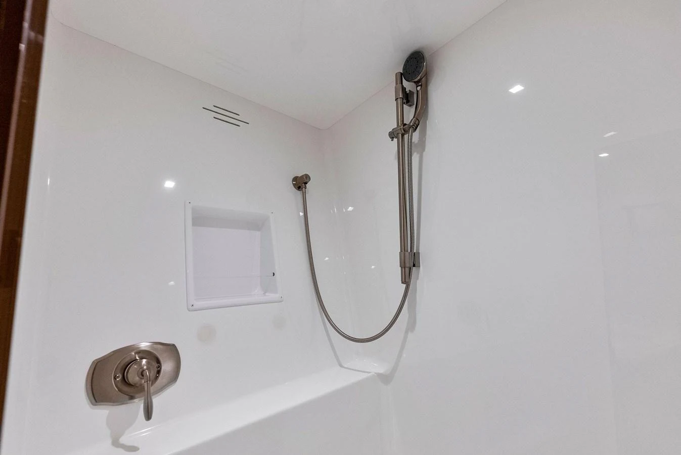 The image shows a sleek and modern shower area with a handheld showerhead and minimalist fixtures. aboard CATCH 23 Yacht for Sale