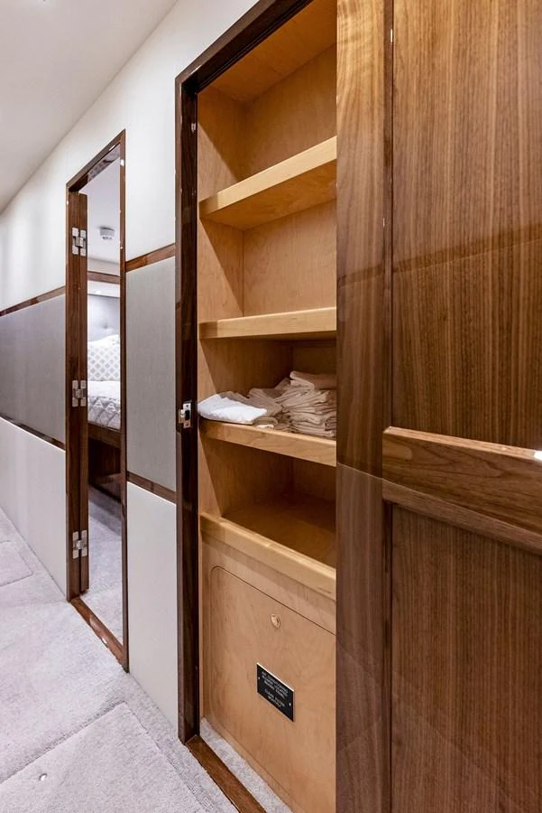 A well-appointed hallway with a built-in wooden storage cabinet and a glimpse into a cozy stateroom. aboard CATCH 23 Yacht for Sale