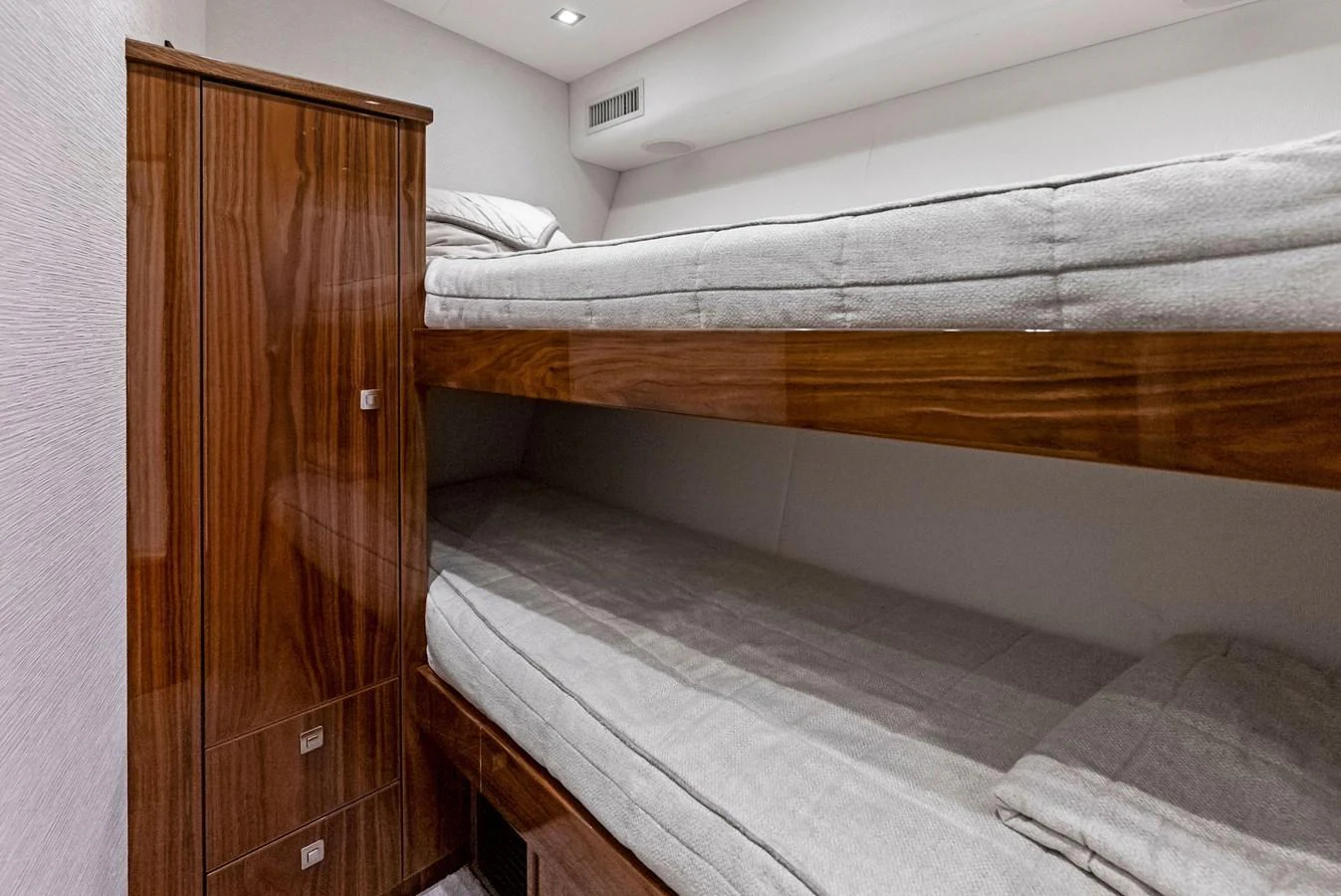 The guest cabin features cozy bunk beds with elegant wooden finishes and soft lighting. aboard CATCH 23 Yacht for Sale