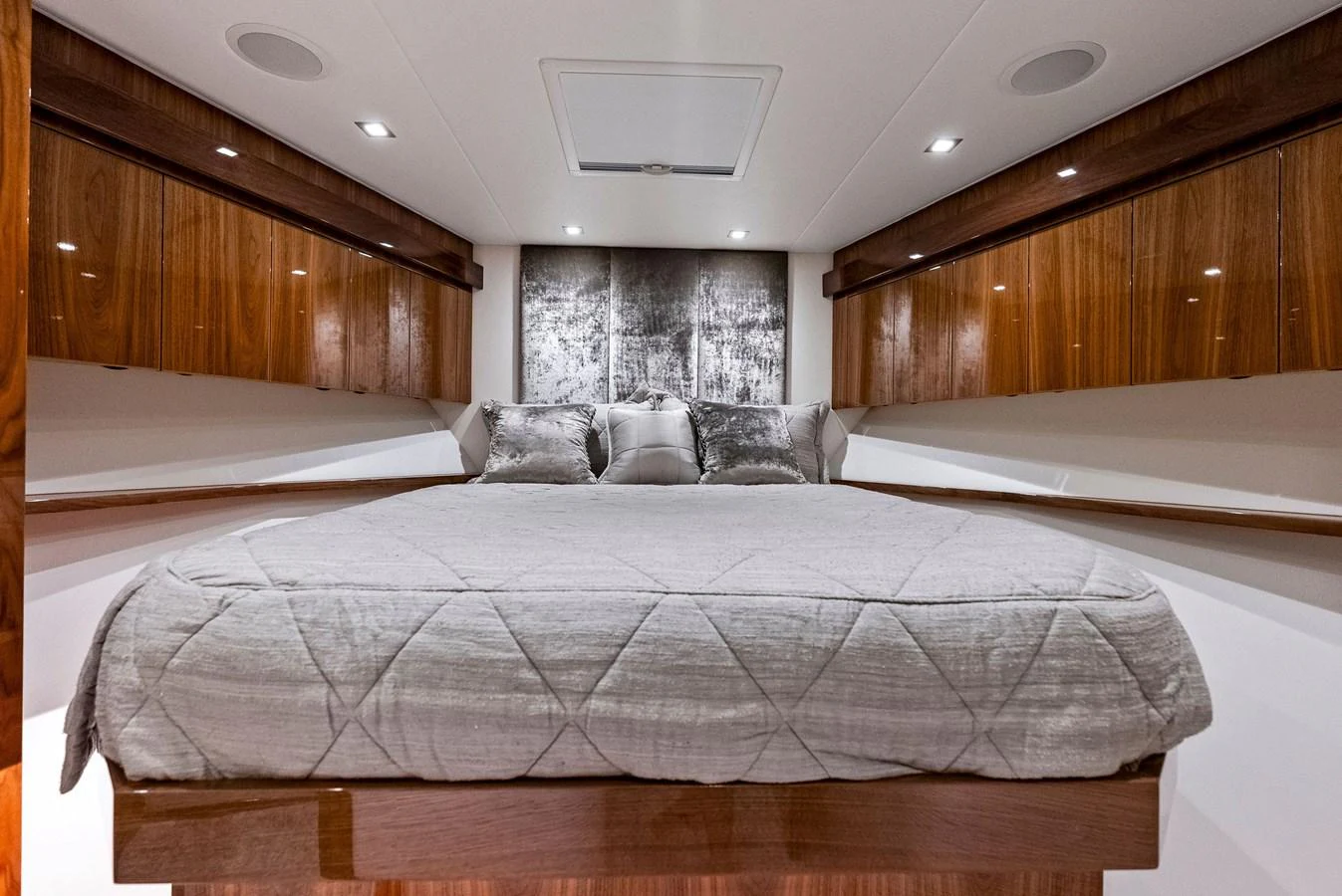 The stateroom features a cozy bed with elegant wood finishes and modern lighting. aboard CATCH 23 Yacht for Sale