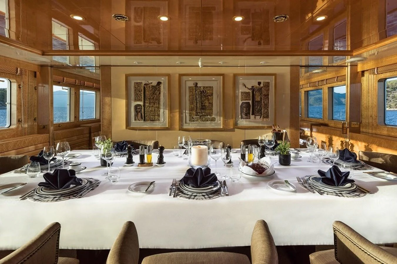 The yacht's dining area features an elegant table setting with panoramic views through large windows. aboard KASSANDRA Yacht for Sale