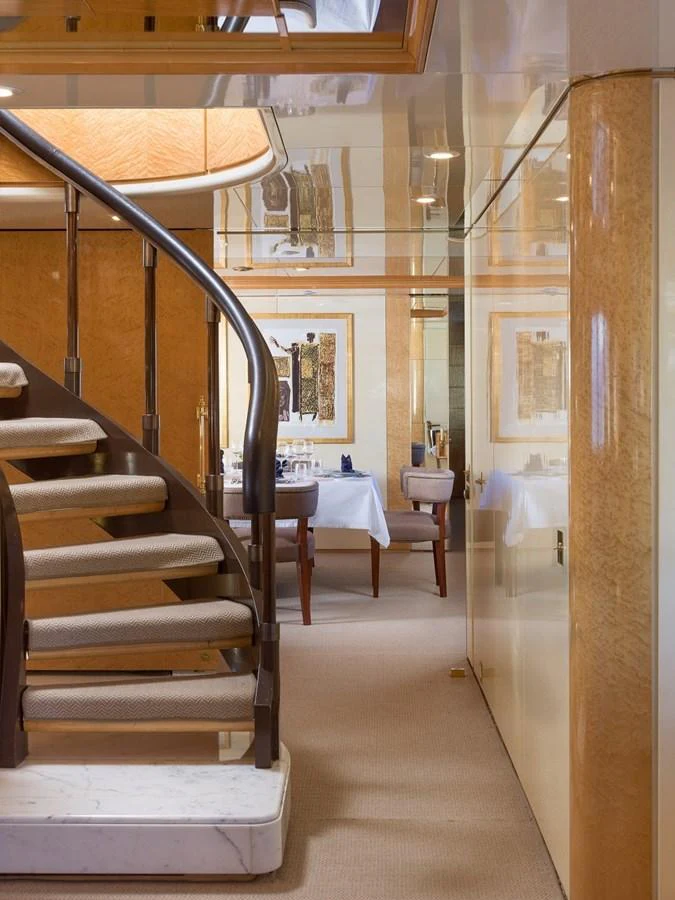 The image showcases a luxurious interior with a stylish staircase leading to a dining area. aboard KASSANDRA Yacht for Sale