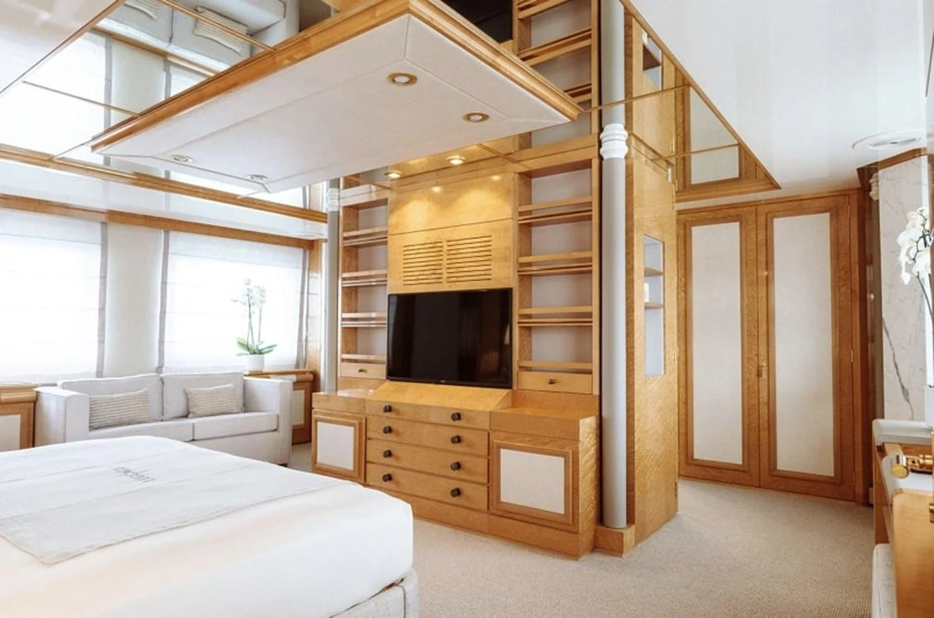 The master stateroom features elegant wood finishes and a spacious layout with a large TV and comfortable seating. aboard KASSANDRA Yacht for Sale