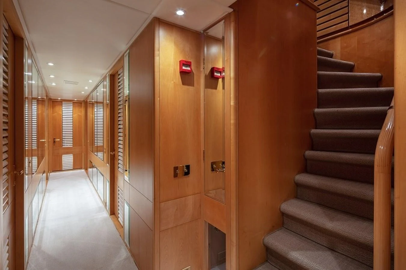 The yacht's interior hallway features warm wood paneling and a carpeted staircase leading to the upper deck. aboard KASSANDRA Yacht for Sale