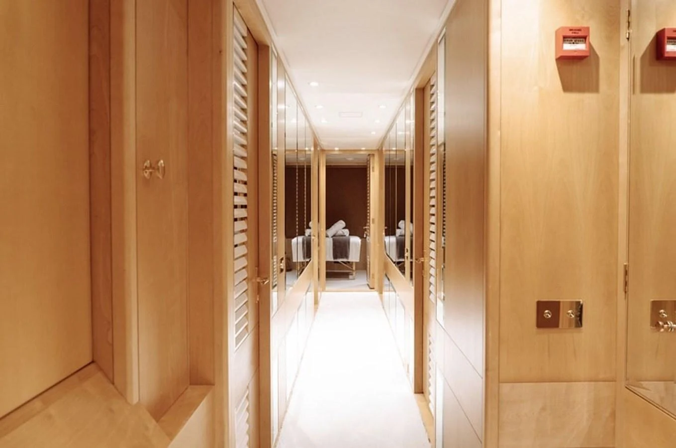 A well-lit hallway with wooden paneling leads to a cozy seating area. aboard KASSANDRA Yacht for Sale