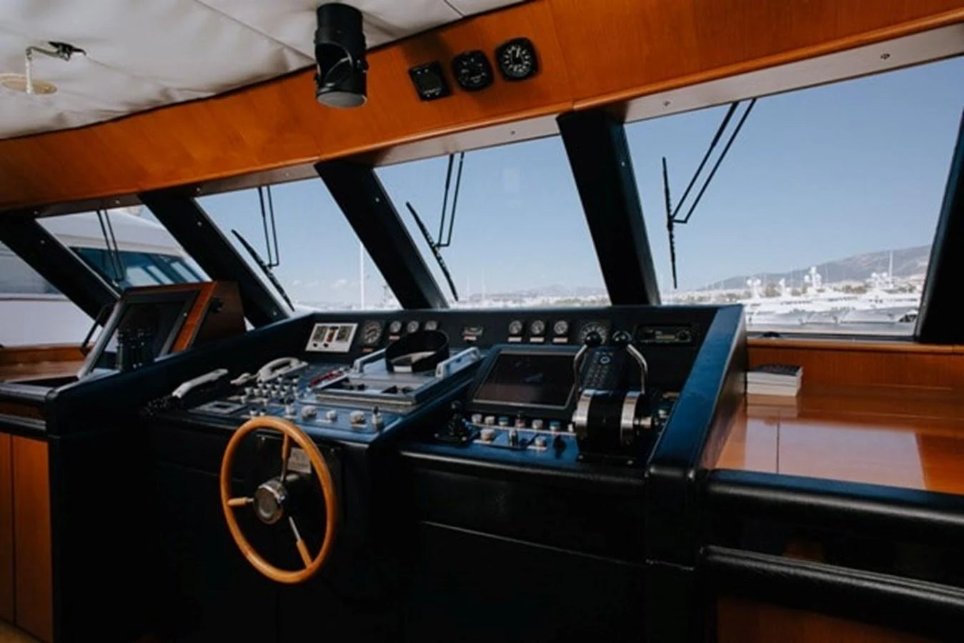 The helm station features a sophisticated array of navigation instruments and a classic wooden steering wheel. aboard KASSANDRA Yacht for Sale