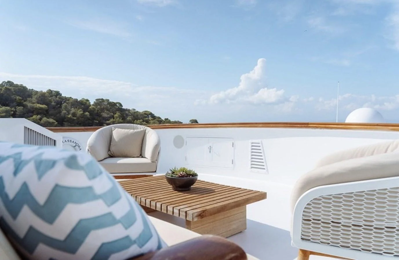 The sundeck offers a serene outdoor seating area with plush chairs and a wooden table, perfect for relaxation. aboard KASSANDRA Yacht for Sale
