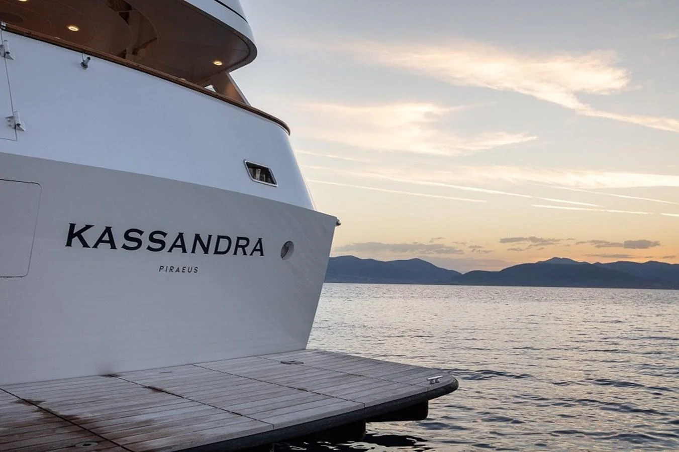The yacht is docked at a serene waterfront during sunset. aboard KASSANDRA Yacht for Sale
