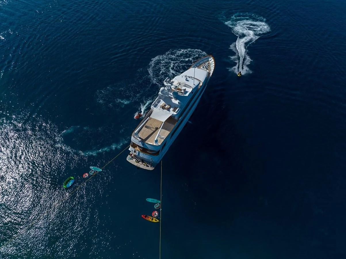 Aerial view of a luxurious yacht anchored in deep blue waters, with various water toys and a jet ski in action nearby. aboard KASSANDRA Yacht for Sale