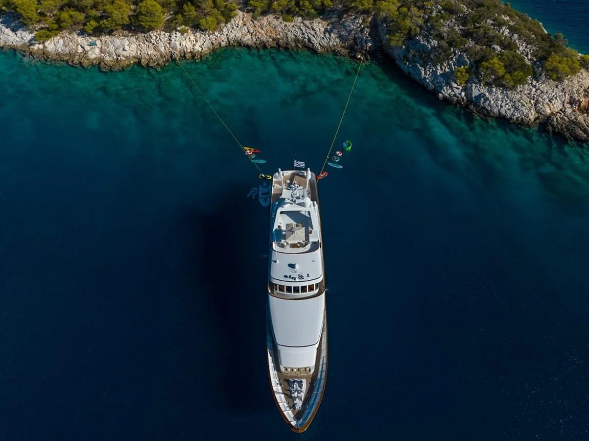 A luxurious yacht is anchored in a serene, turquoise bay surrounded by lush greenery. aboard KASSANDRA Yacht for Sale