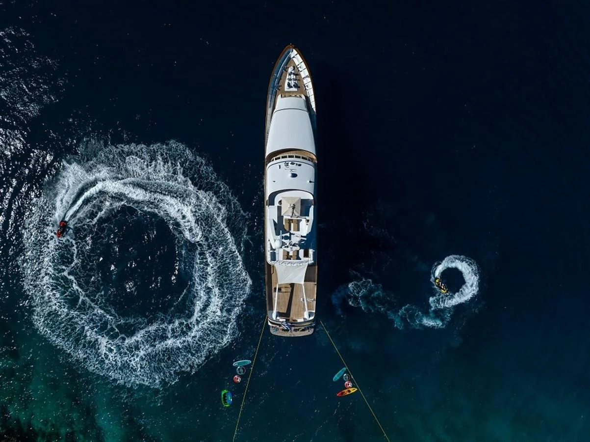 Aerial view of a yacht anchored in deep blue water with water sports activities around. aboard KASSANDRA Yacht for Sale