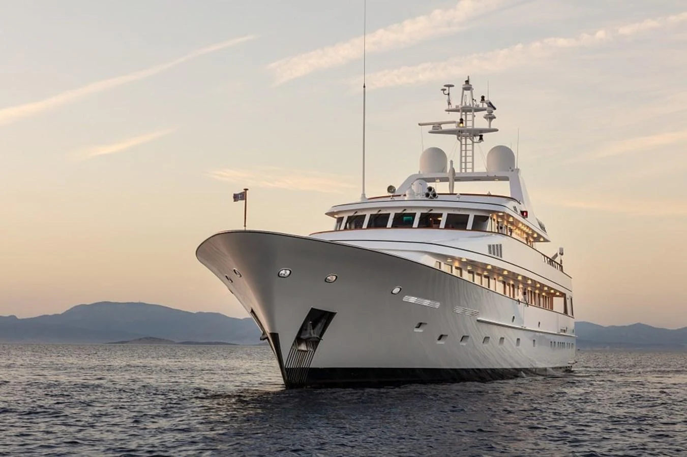 A stunning yacht glides gracefully on calm waters at sunset, showcasing its sleek design and luxurious features. aboard KASSANDRA Yacht for Sale