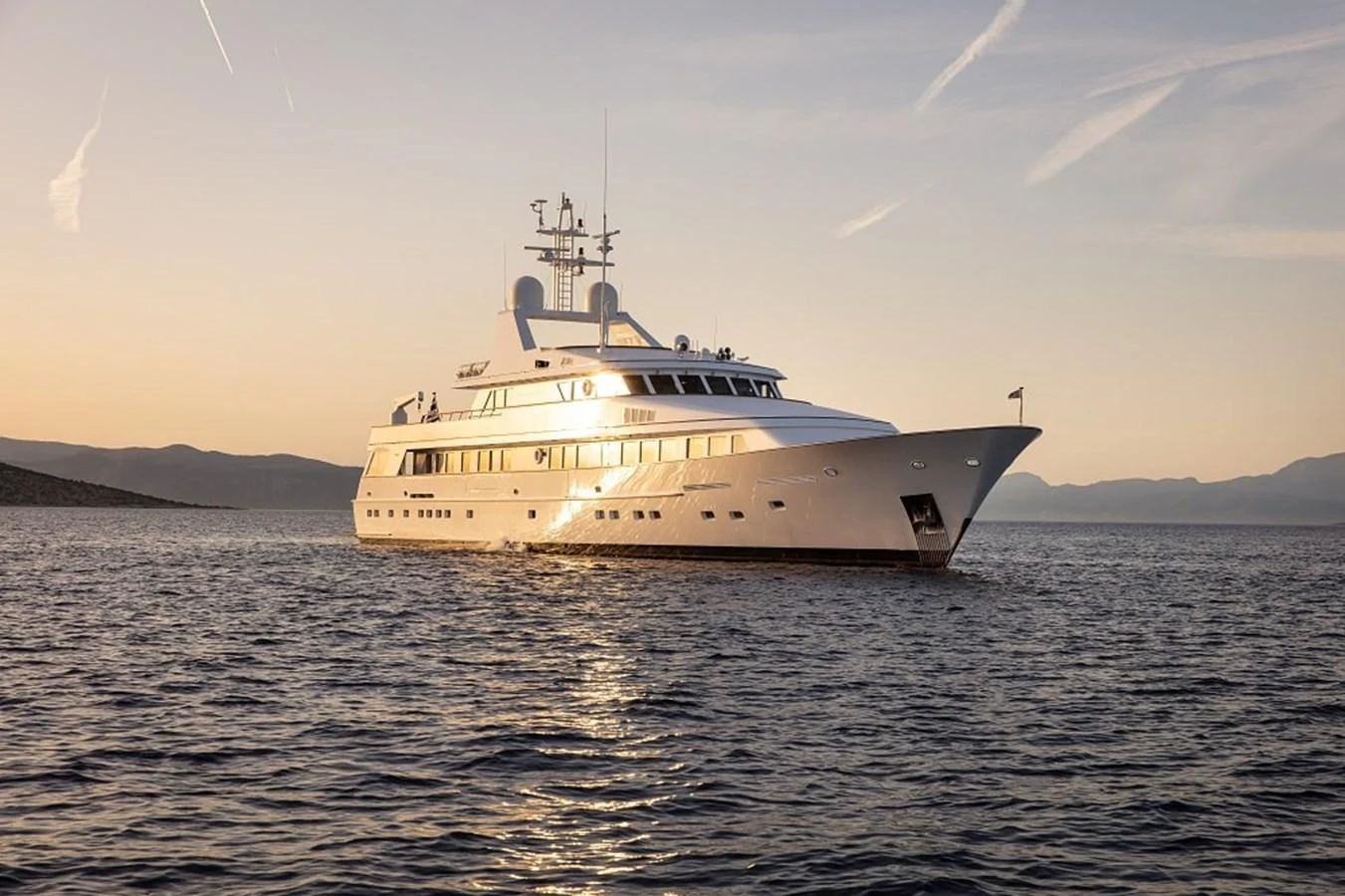 A luxurious yacht glides gracefully on calm waters at sunset. aboard KASSANDRA Yacht for Sale